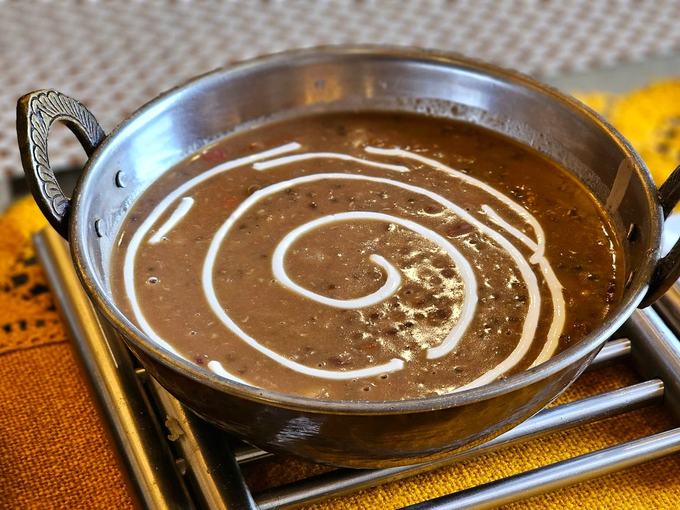 Dal makhani in a steel bowl, a spiral of cream through the black lentils.