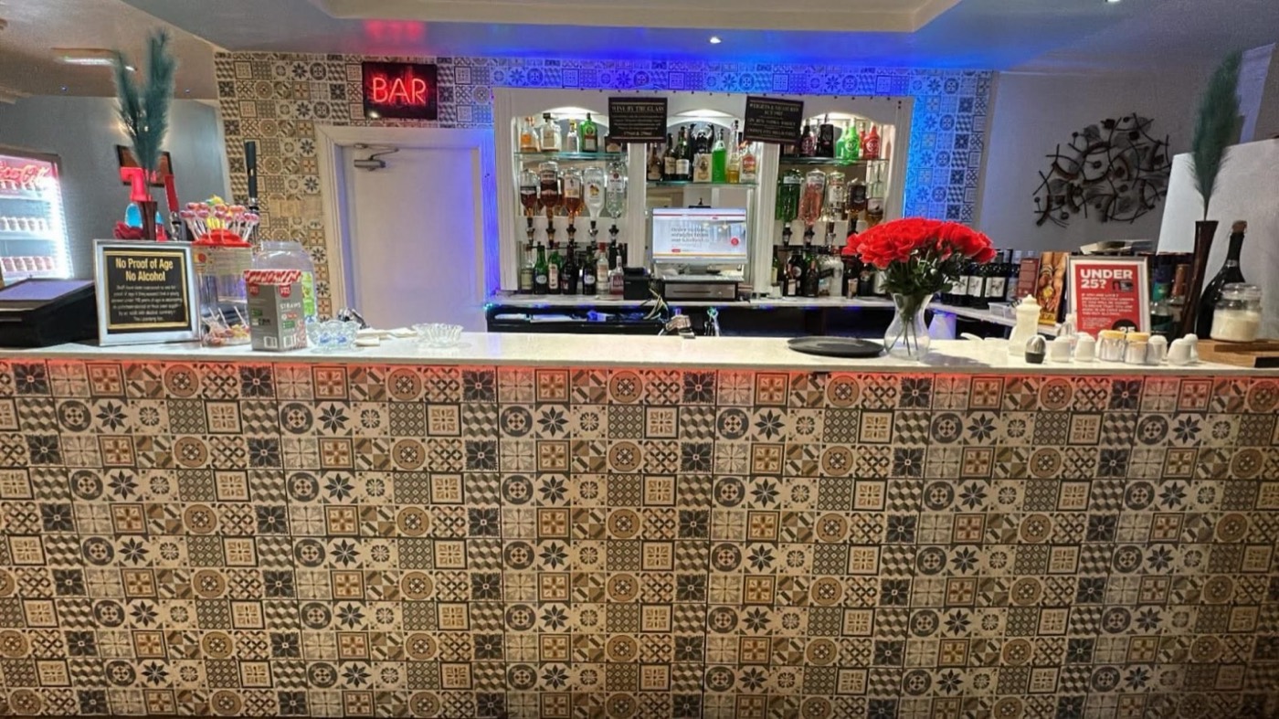 The bar, faced in patterned tiles and lit from below, with the spirits shelved behind it.