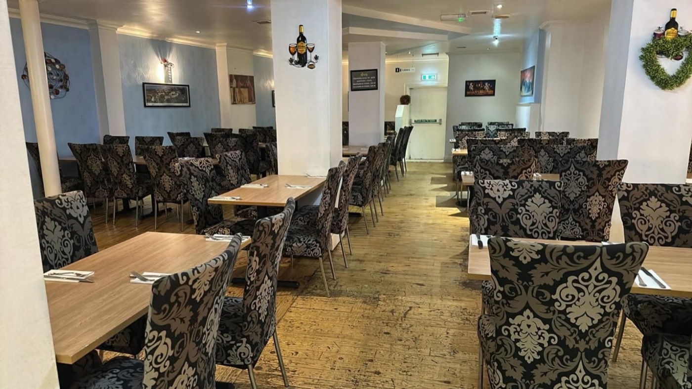 The long side of the dining room, pale blue walls and tables laid with cutlery down the length of it.